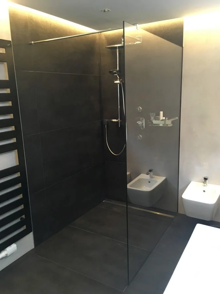 Begehbare Glasdusche mit dunklen Fliesen