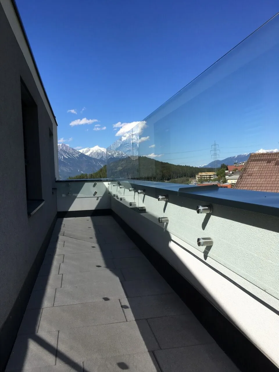 Glasgeländer entlang eines langen Balkons mit Blick auf die Berge