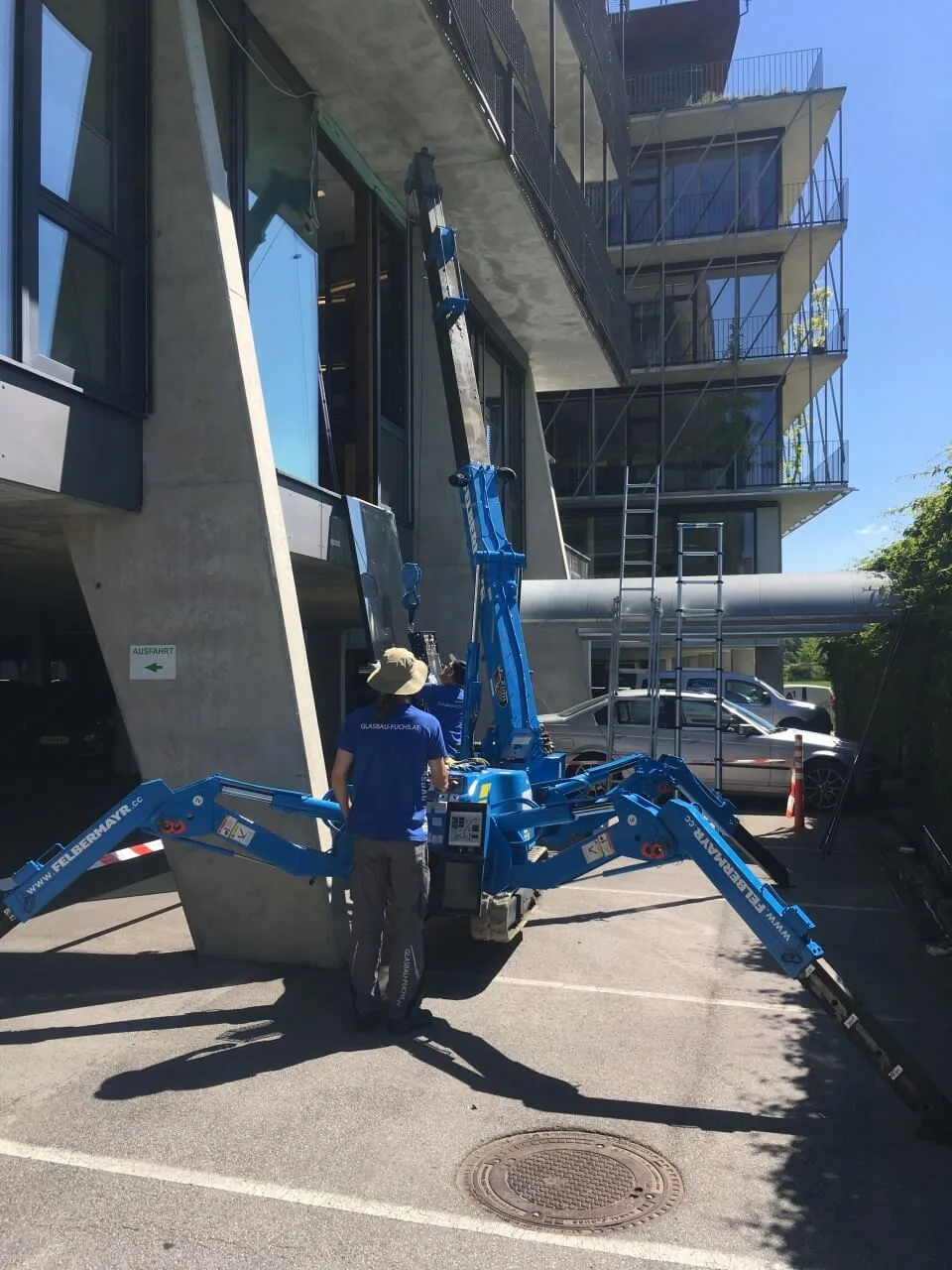 Monteur bedient einen Spinnenkran vor einem Neubau