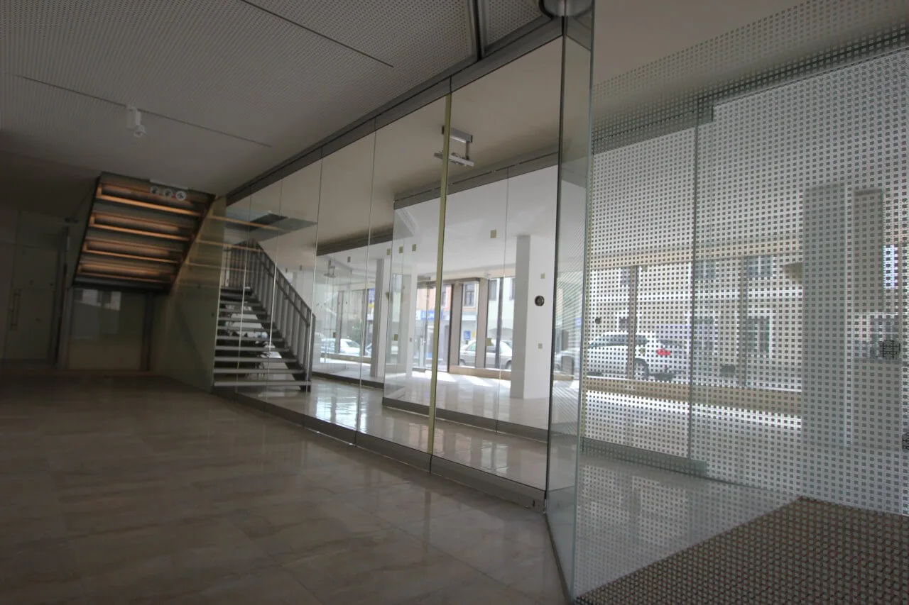 Ganzglasanlage mit Ganzglastüren in einer Eingangshalle, daneben eine Treppe