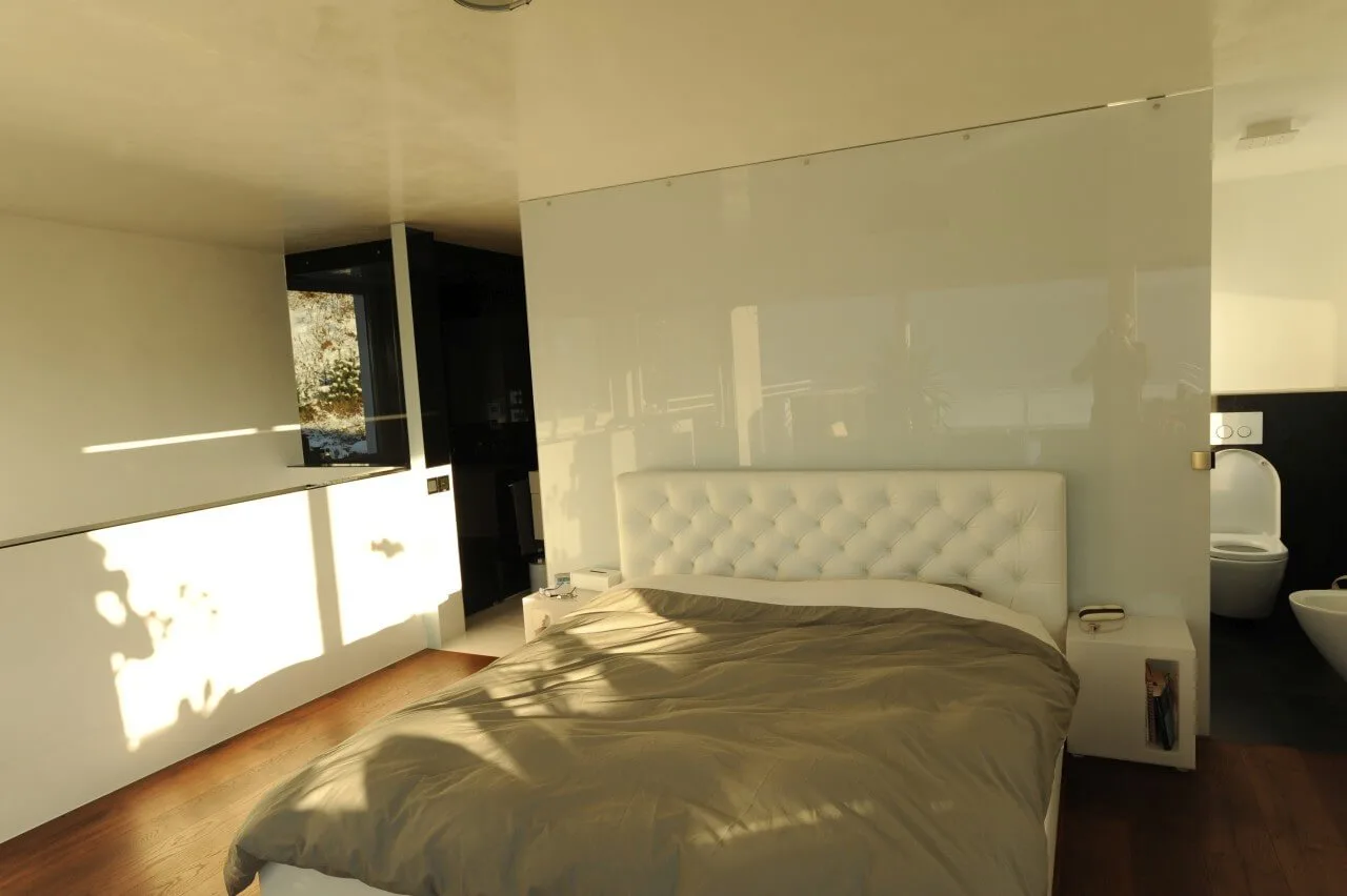 Weiße Glaswand als Raumteiler in einem Schlafzimmer