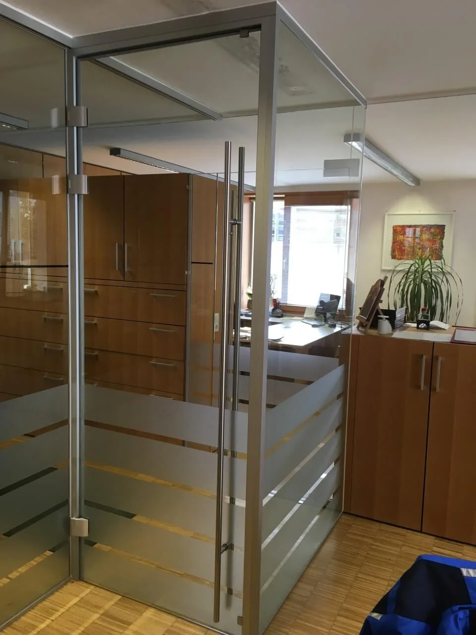 Büroverglasung aus Glas mit Streifenfolie und einer Ganzglastür mit Stangengriffen